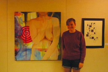 Ardys Woodward, sophomore, poses next to her artwork at the "Tolerance and the Other" student art exhibit.