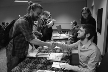 Sophomore Isaiah Friesen shakes the hand of senior Kolton Nay after purchasing his pinchpenny novel at Tuesday’s release party.