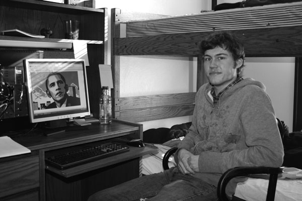 Black and white image of Dirk Miller sitting next to a photo of President Obama on a computer