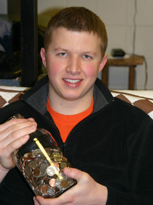 Aaron Shenk holds a Mason jar filled with coins