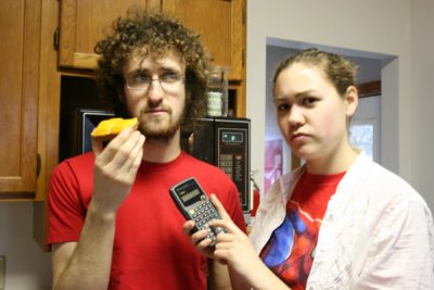 Chase Snyder holds up a pastry as Lydia Short holds up a calculator next to him