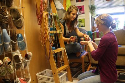 Erica Grasse shows paper-bead necklaces hanging from a ladder in her dorm room to a potential buyer