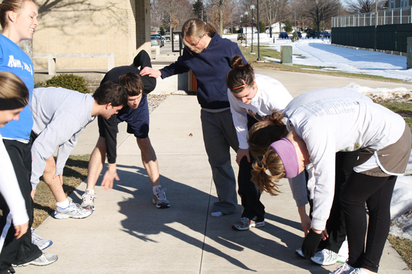 Students rest their elbows on their knees to take a breather after practicing for a half-marathon