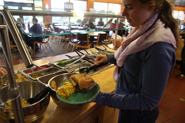 A student fills their plate with food from the Rott