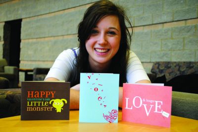 Emma Brooks poses with three of her hand-designed cards