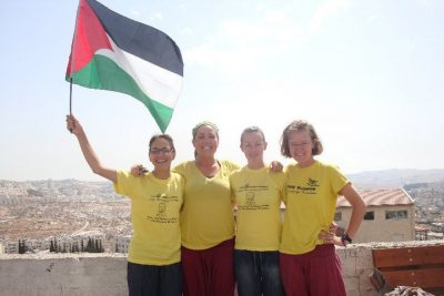Liz Berg and three other people wave the Palestinian flag
