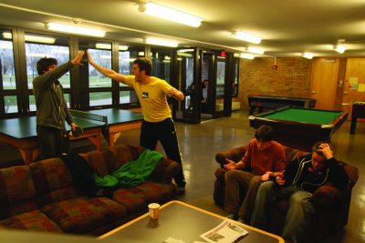 students high five in game room watching march madness