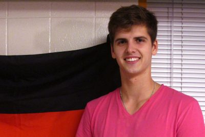 Jan Zawadzki stands next to a German flag in his dorm room