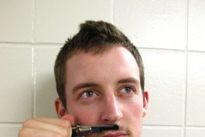 Jonathan Hershberger holds a clipper under his nose in place of a mustache