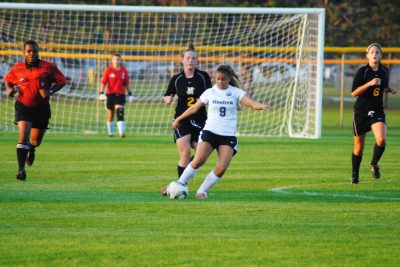 A player on the Goshen women's soccer team dribbles the ball away from opposing players during a game