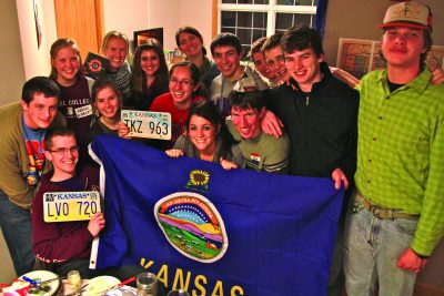 Members of Kansas Club hold up Kansas license plates and the Kansas flag