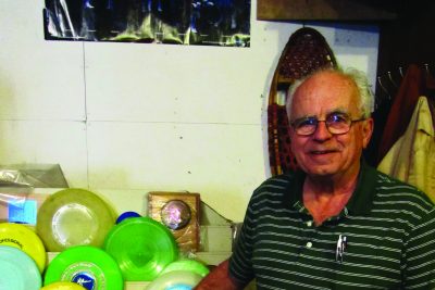 Jim Ingold stands next to his large Frisbee collection