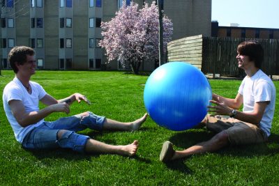 Two students play with a bouncy ball on the KMY lawn