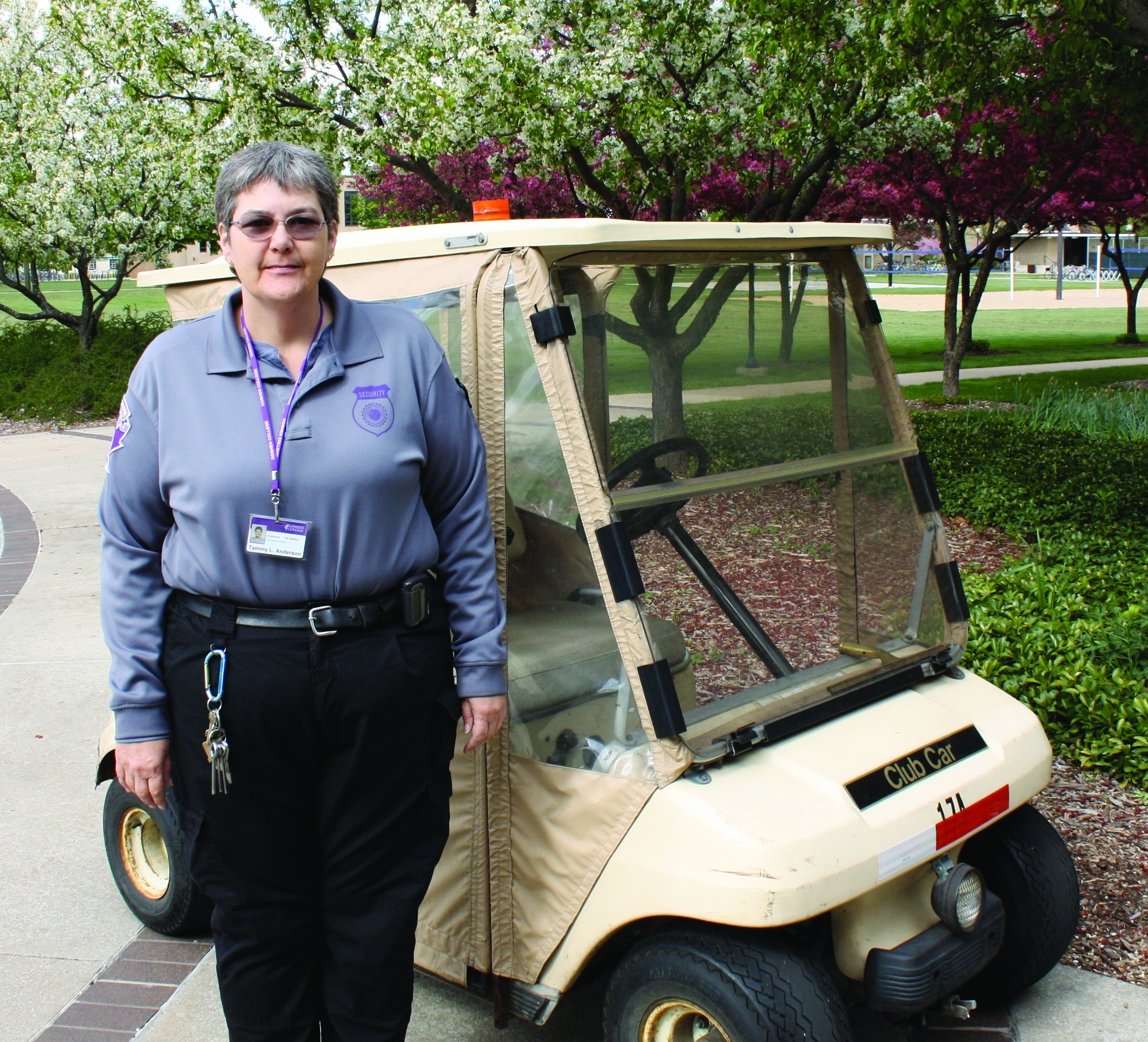 Tammy Anderson stands in front of a golf cart in her campus security uniform