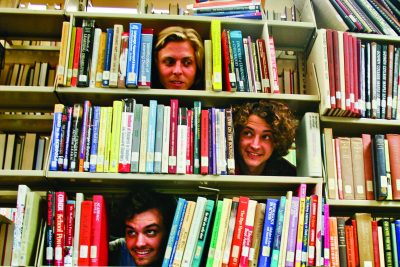 Kansas Bible Company members Charlie Frederick, Nate Klink, Jacob Martin and Jeff Yoder pose for a funny picture, sticking their heads through open spaces in bookshelves in the Good Library