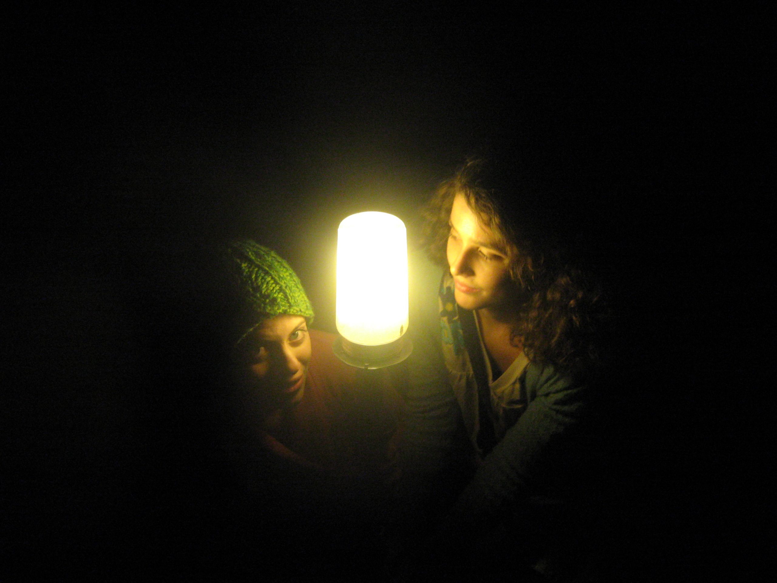 Natalie Hartman and Emily Kraybill pose with half of their faces illuminated by the ghost's light in Umble Center