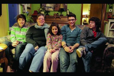 Jillian De Moya sits on the couch of her family home alongside her four children