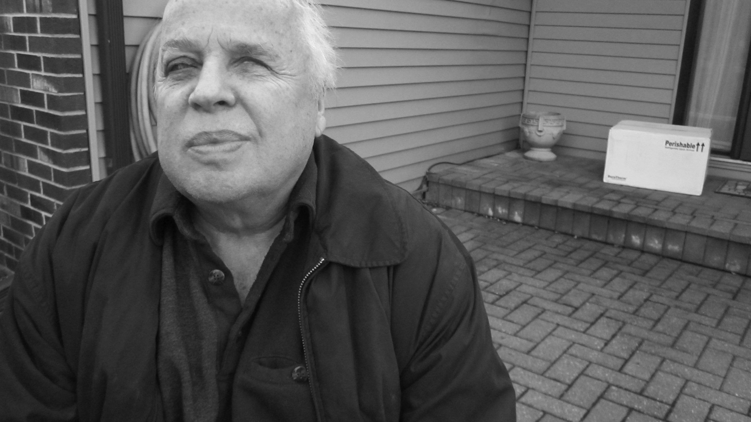 Black and white image of Marvin Graber sitting on his porch