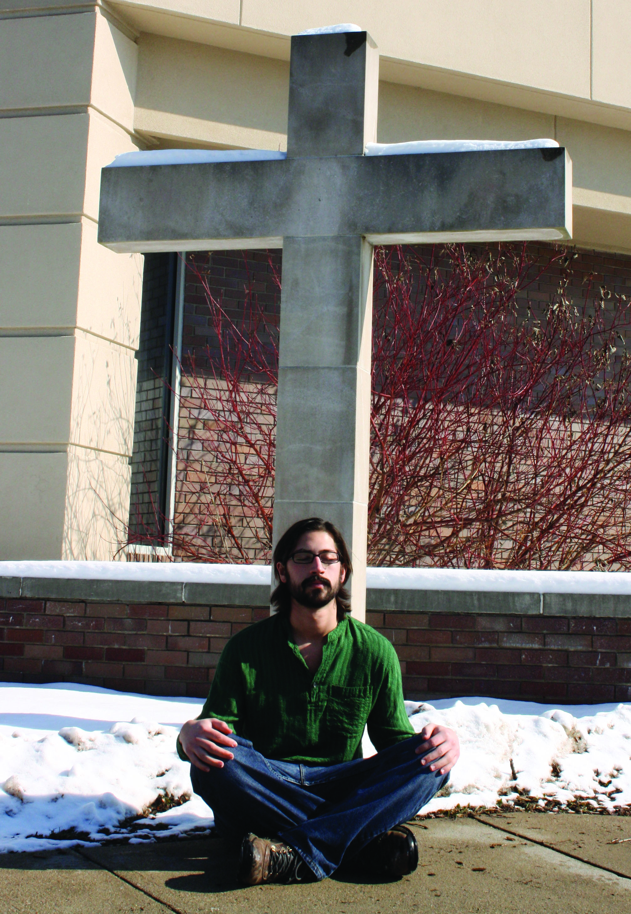 Mike Zehr sits in a meditative position in front of the cross outside of Church Chapel