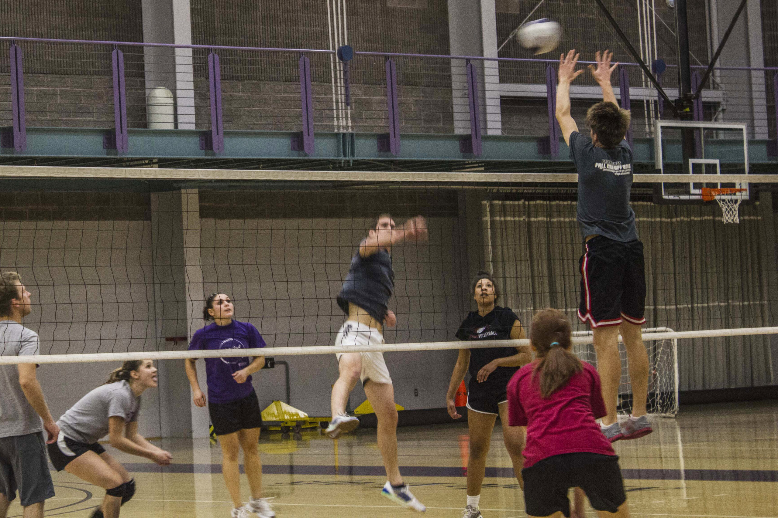 A player from the Compassionate Killers spikes the ball to Block Market during an intramural volleyball game