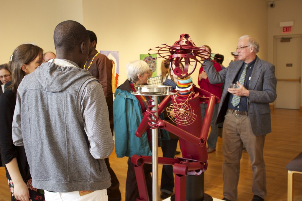 Reception attendees gather around Sunday Mahaja's sculpture entitled "Housa Man." 