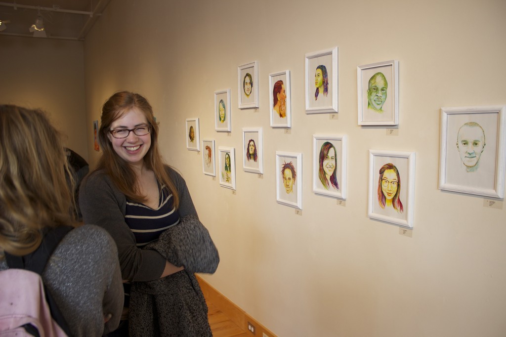 Kate Yoder, a junior, stands in front of portraits by Liz Reese.