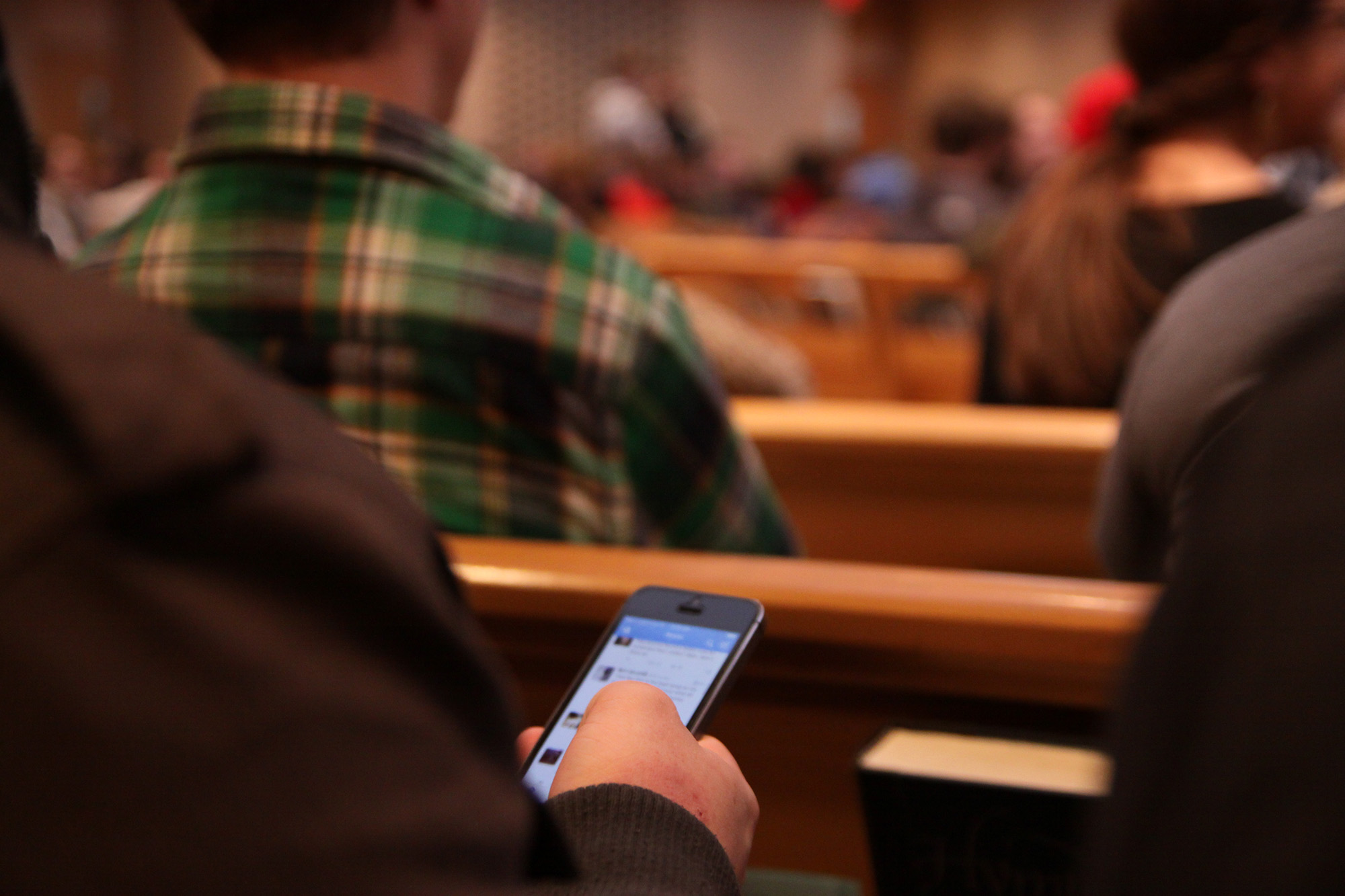 Close-up shot of a student using their phone during a chapel service