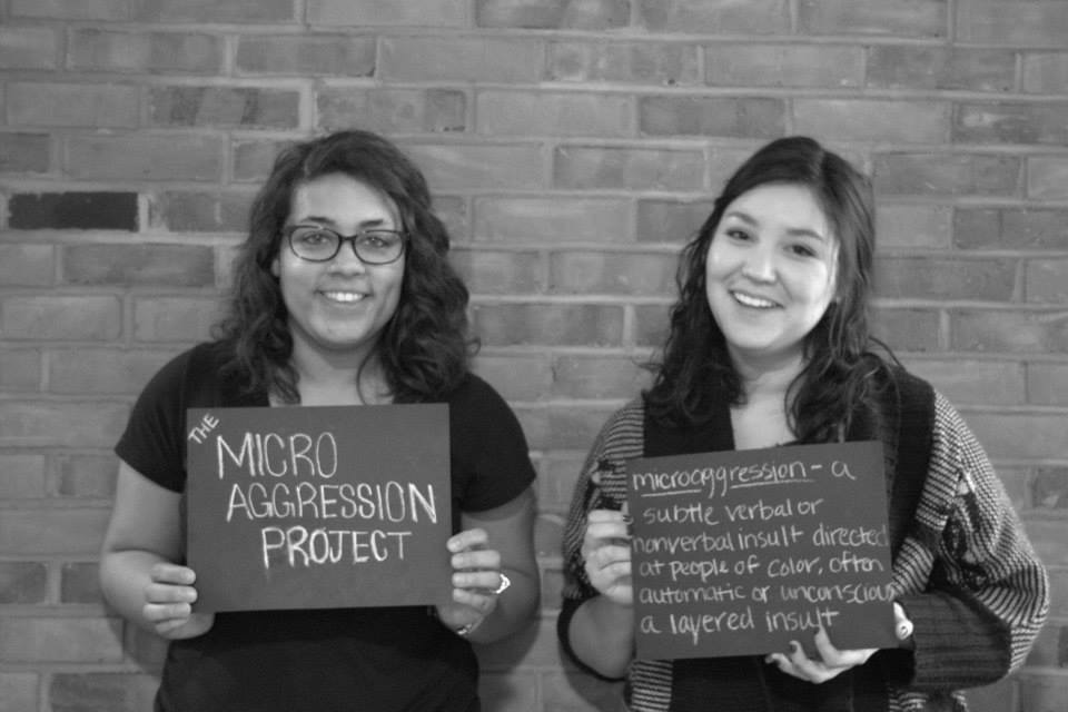 Students posing with microaggressions signs