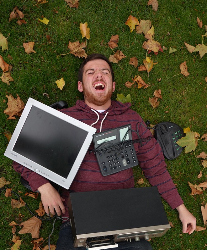 Overhead shot of Brian Sutter lying on the lawn surrounded by laptops and other electronic devices