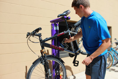 A student brings their bike to the new purple Goshen bike repair station