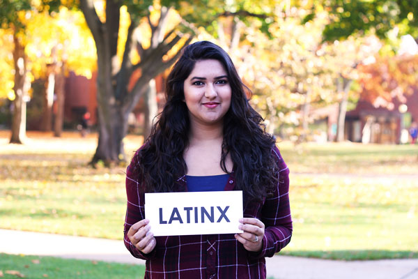 Alexa Valdez holds a white card reading "LATINX" in black letters