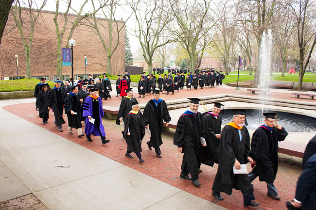 Graduated students walk through Shrock Plaza in their caps and gowns