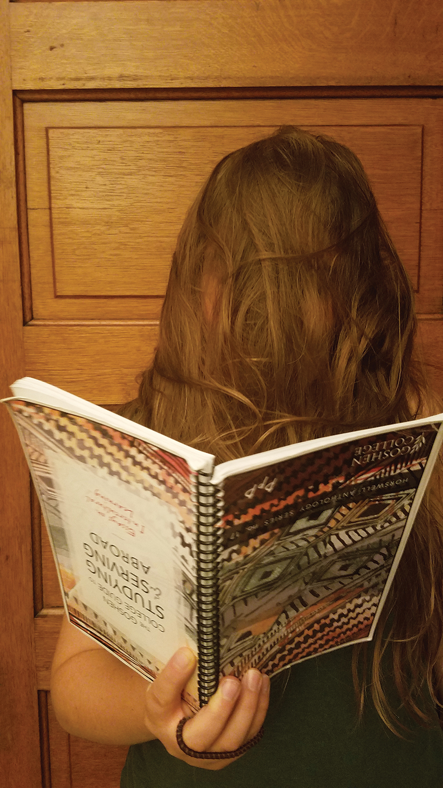 Katie Yoder covers her face with her hair while reading an upside down book