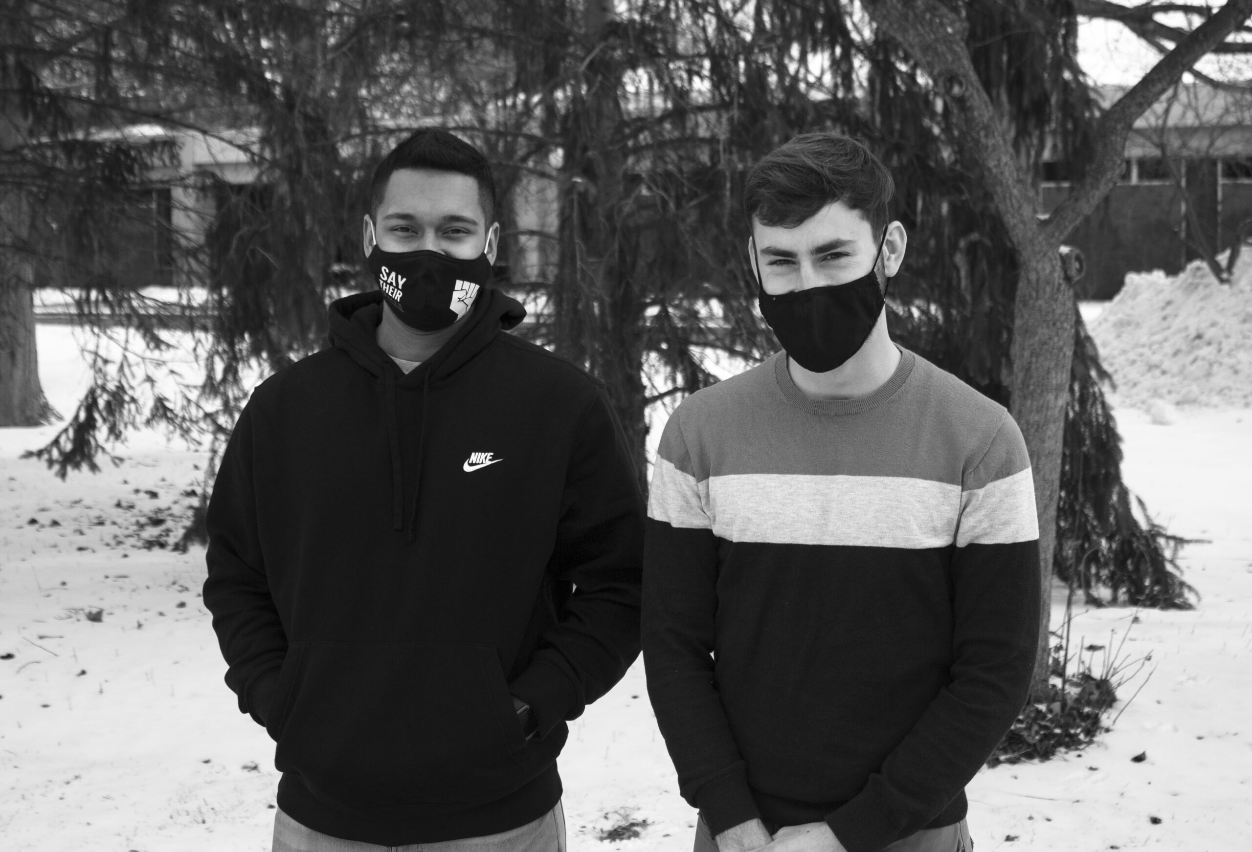 Black and white image of Ronit Goswami and Wes Beck. The two are standing outside in the snow and are both wearing masks