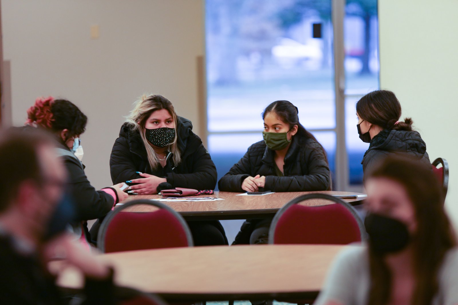 A group of students wear masks at a table during a workshop.