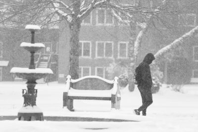 A student walks through campus on a snowy day.
