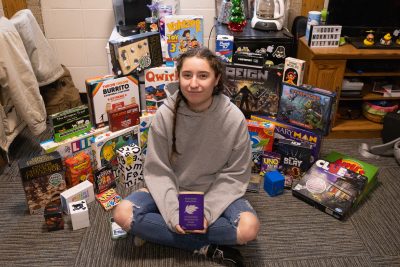 Summer Cooper poses for a picture, surrounded by her collection of board games.