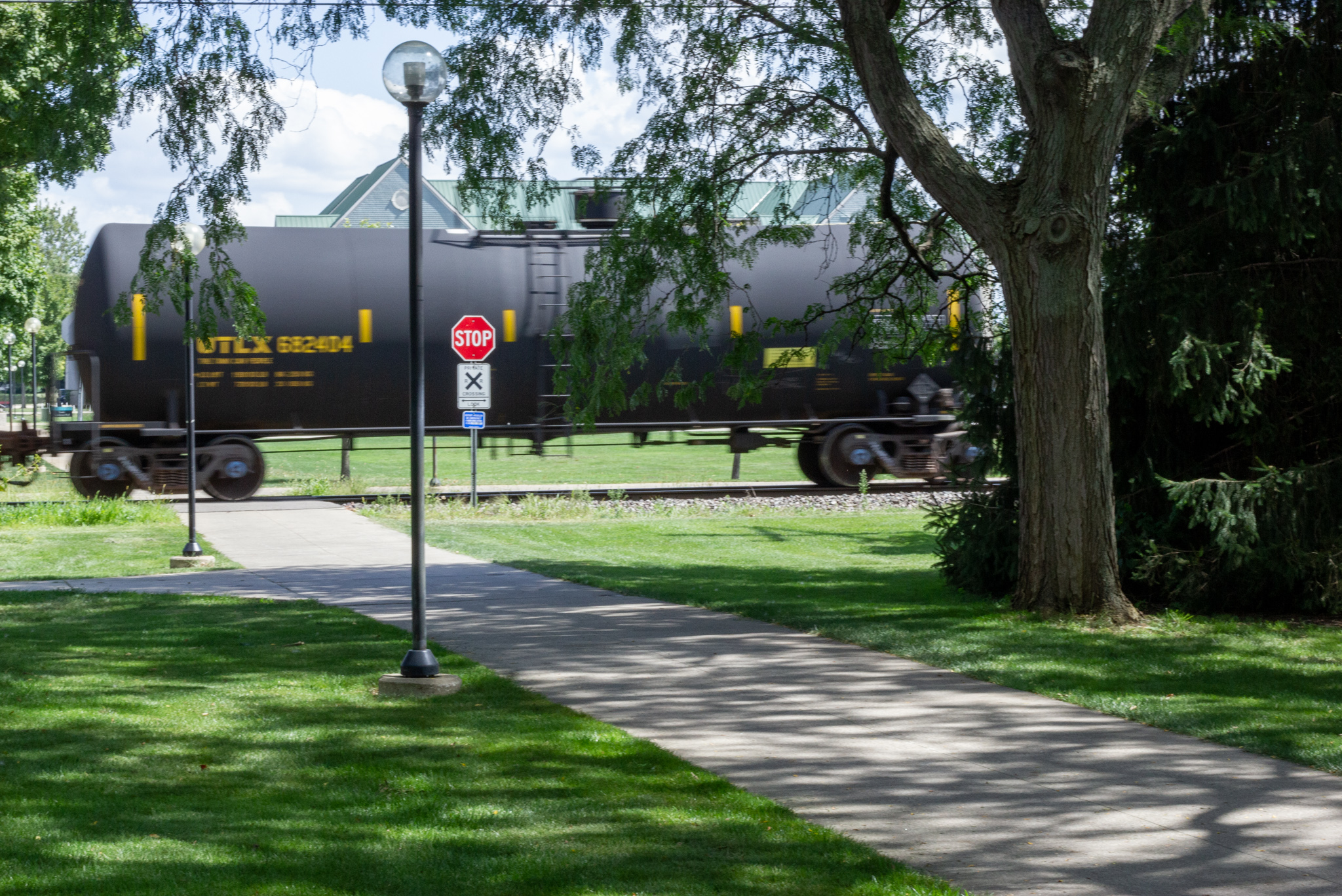 a train thunders through campus. Photo taken from the side shows train cars passing over a sidewalk crossing.